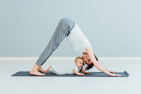 young mother does physical yoga exercises together with her baby boy